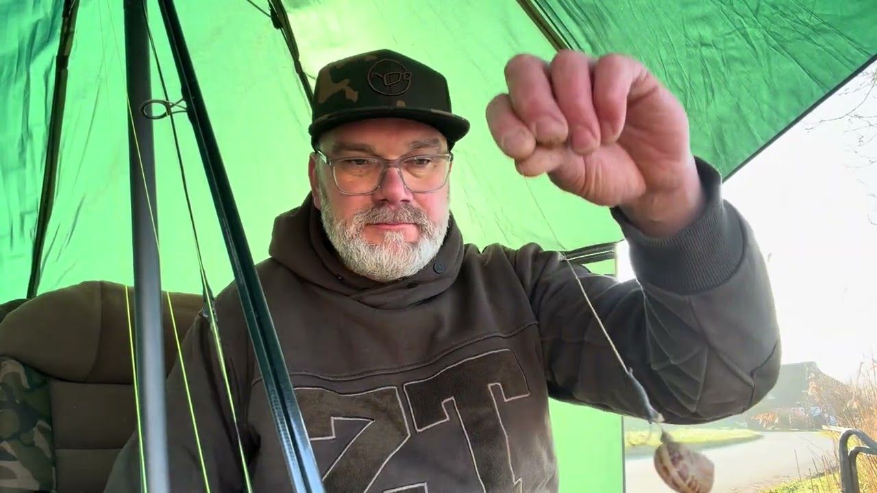 Ich sitze unter dem grünen Schirm und halte eine Montage hoch.